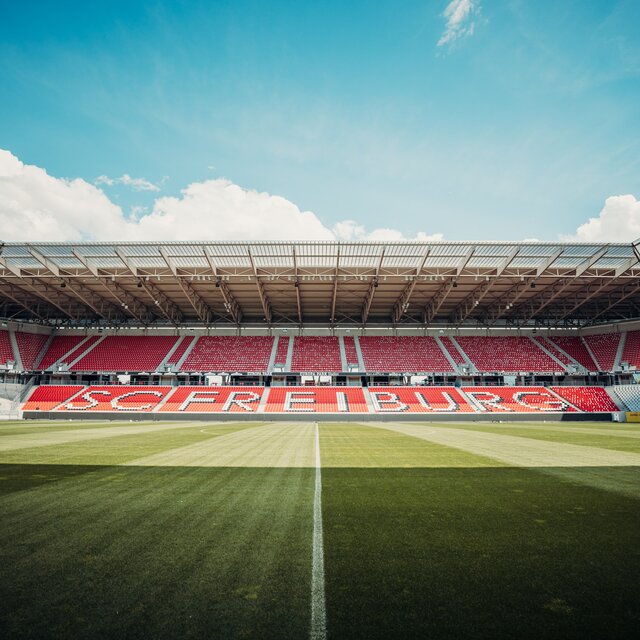 Empty football stadium with grass, stands and red SC Freiburg seats