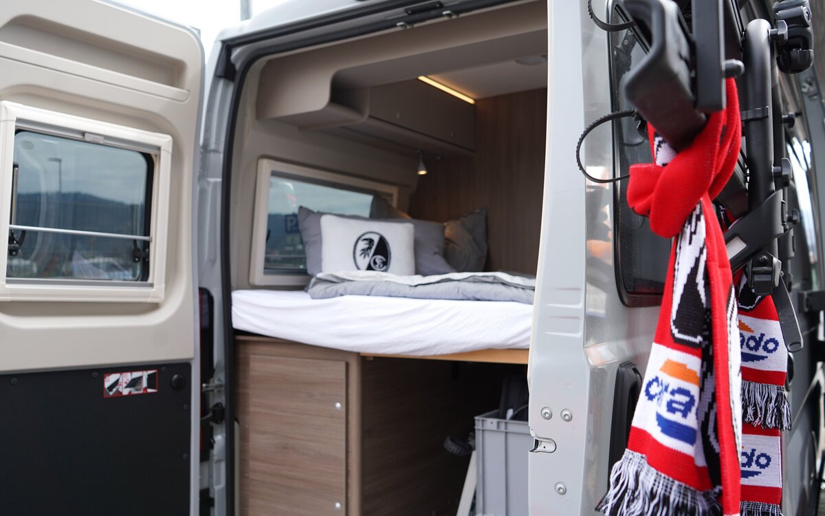 Rear bed in the Carado motorhome with the rear doors open and storage space underneath
