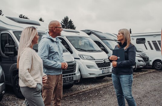 Consultation in front of several Carado motorhomes at a dealer's premises