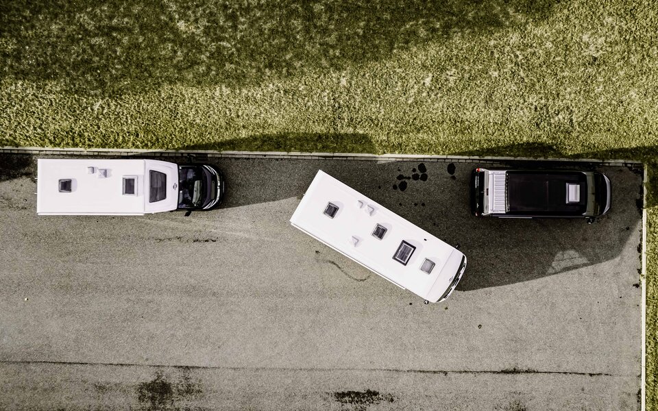 Drone view of two Carado motorhomes parking on asphalt beside a black camper van