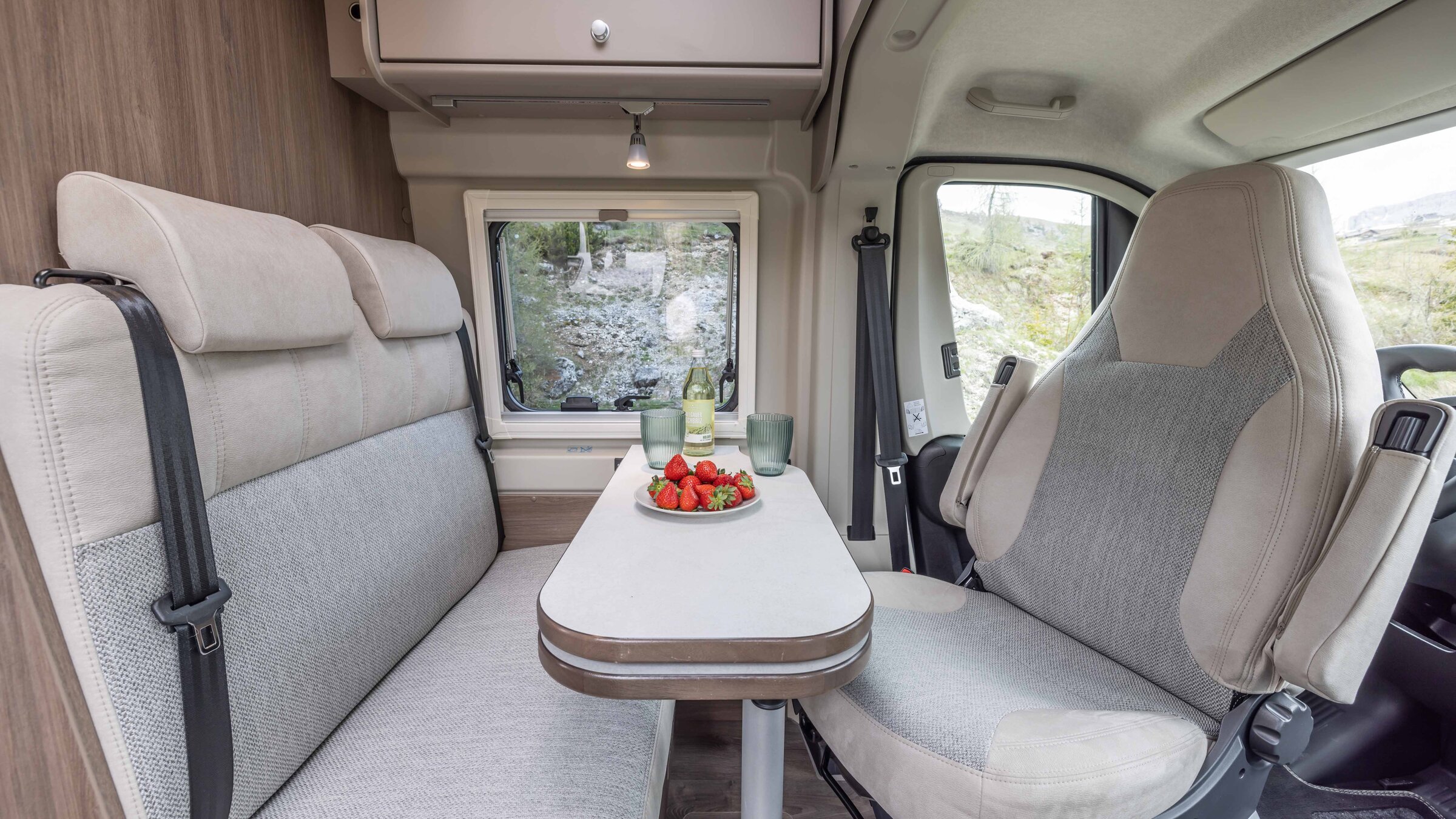 Zithoek in de Carado camper met tafel, bank, draaibare voorstoel en raam