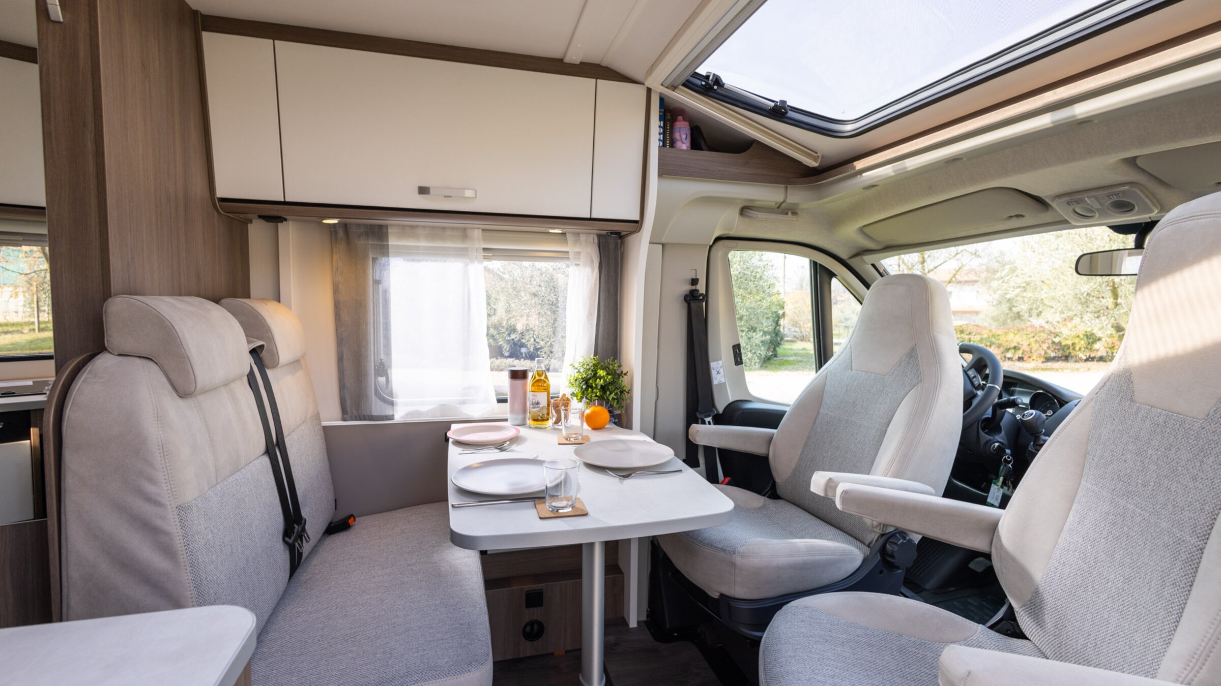 Interieur van de Carado camper met zithoek, draaibare cabinestoelen, tafel en dakraam