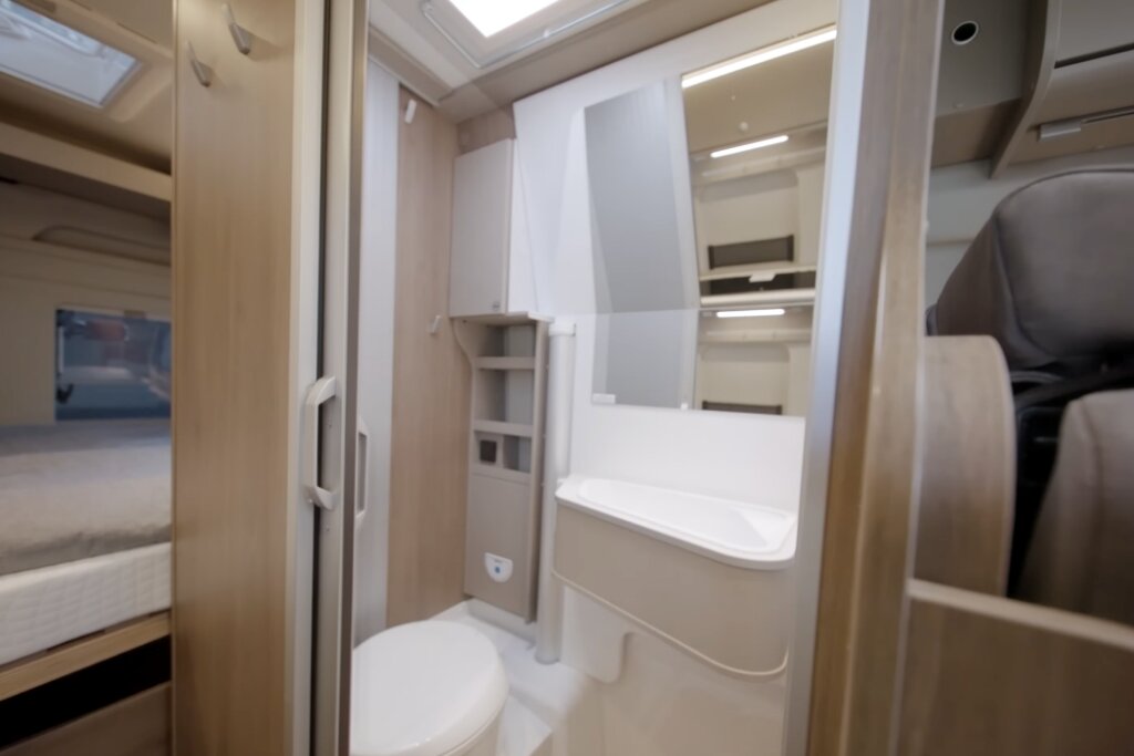 Carado motorhome bathroom with washbasin, mirror, toilet and a view of the sleeping area