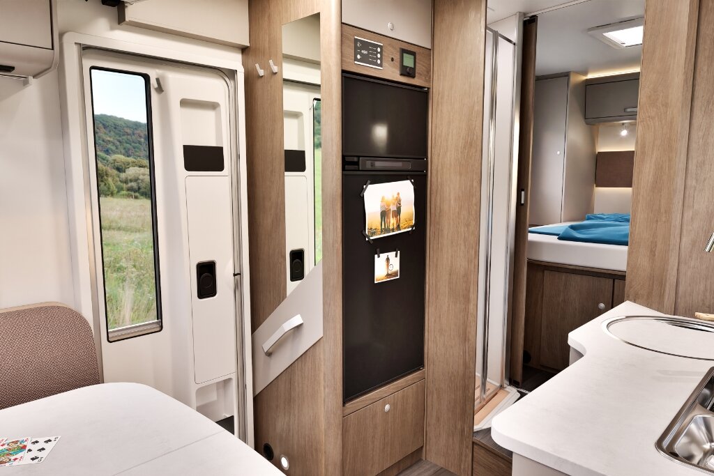Carado motorhome interior with refrigerator, kitchen, entrance door and a view of the rear bed