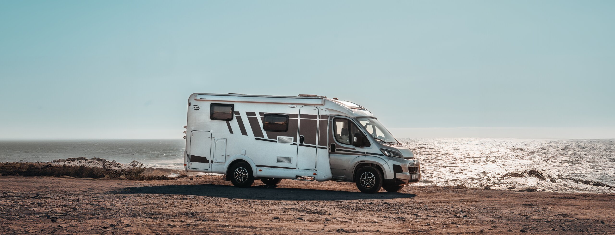 Carado campervan in zijaanzicht op een rotsachtige kustplaats aan zee
