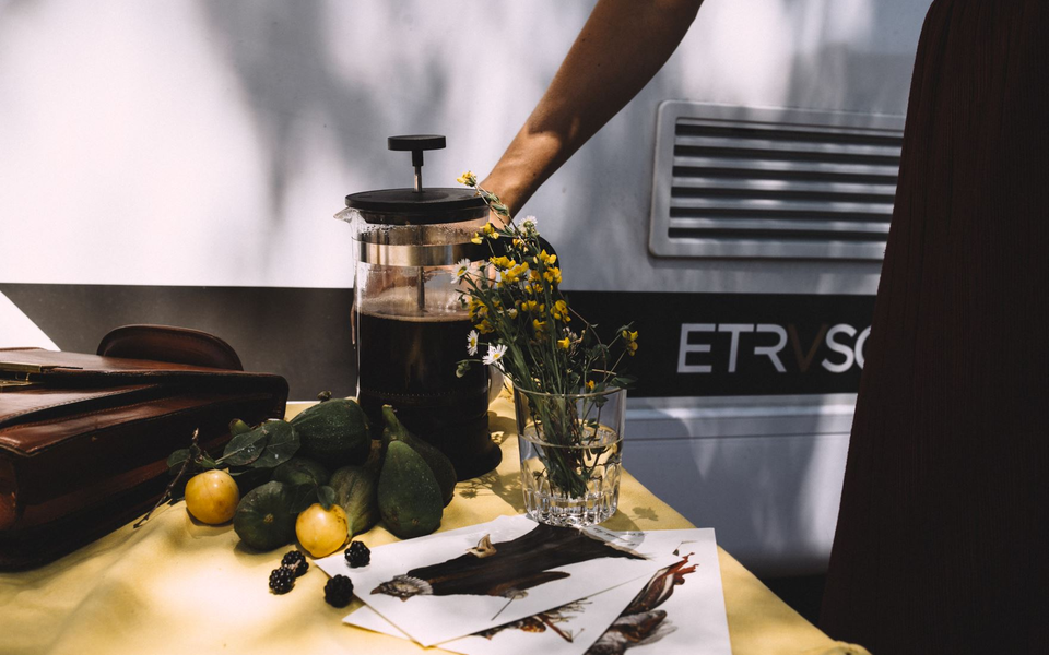 Camping scene with fresh lemons, flowers, and a coffee pot on a table in front of an Etrusco motorhome, ideal for relaxing moments.