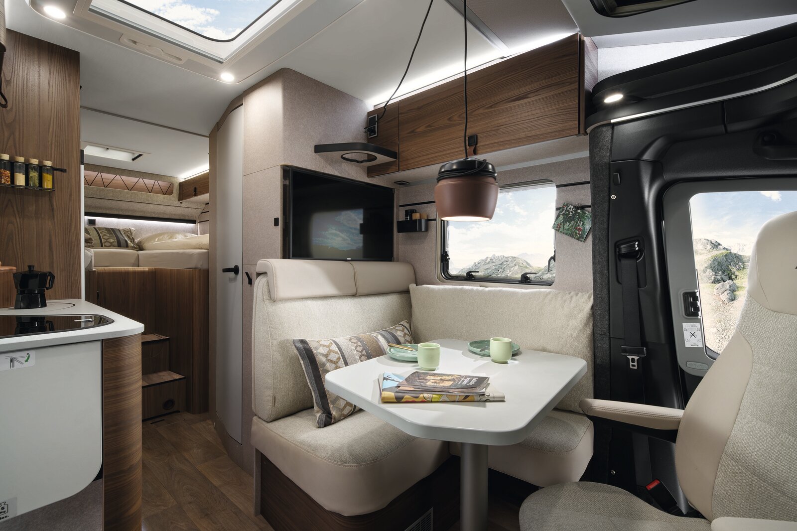 On the table inside the style world Native Bamboo of the HYMER ML-T, there are snacks, water glasses, a pair of glasses, and some coasters.