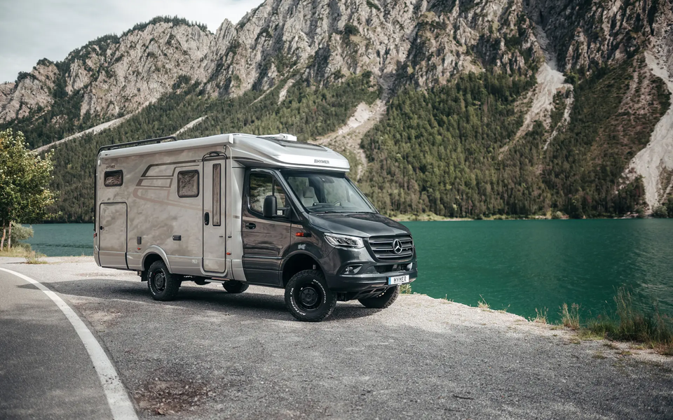 The HYMER ML-T is slightly turned in front of a mountain lake.