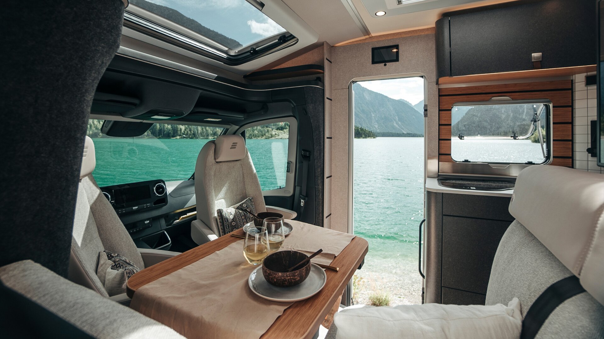 Looking through the interior of the HYMER ML-T in the Native Bamboo style, numerous windows and doors provide a view of the landscape.