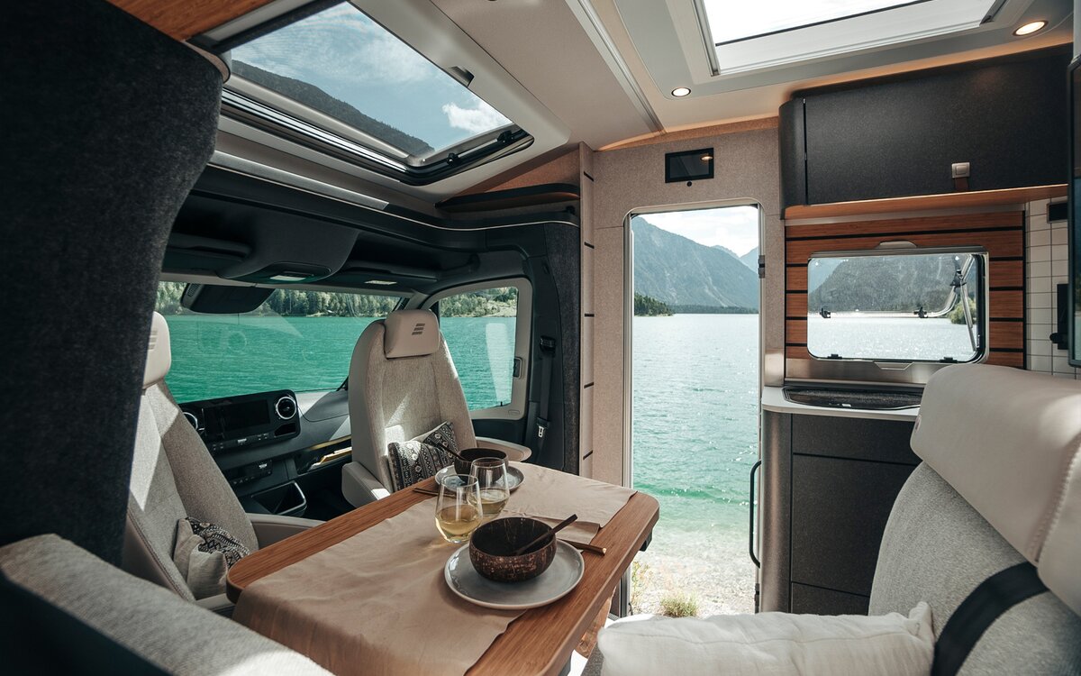 Looking through the interior of the HYMER ML-T in the Native Bamboo style, numerous windows and doors provide a view of the landscape.