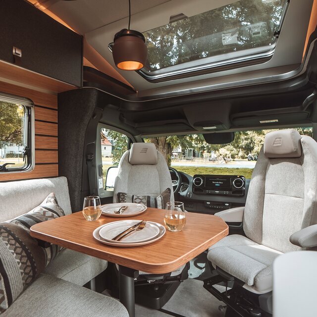 The table in the living area of the HYMER ML-T is set. The multifunctional light has been mounted above the table.