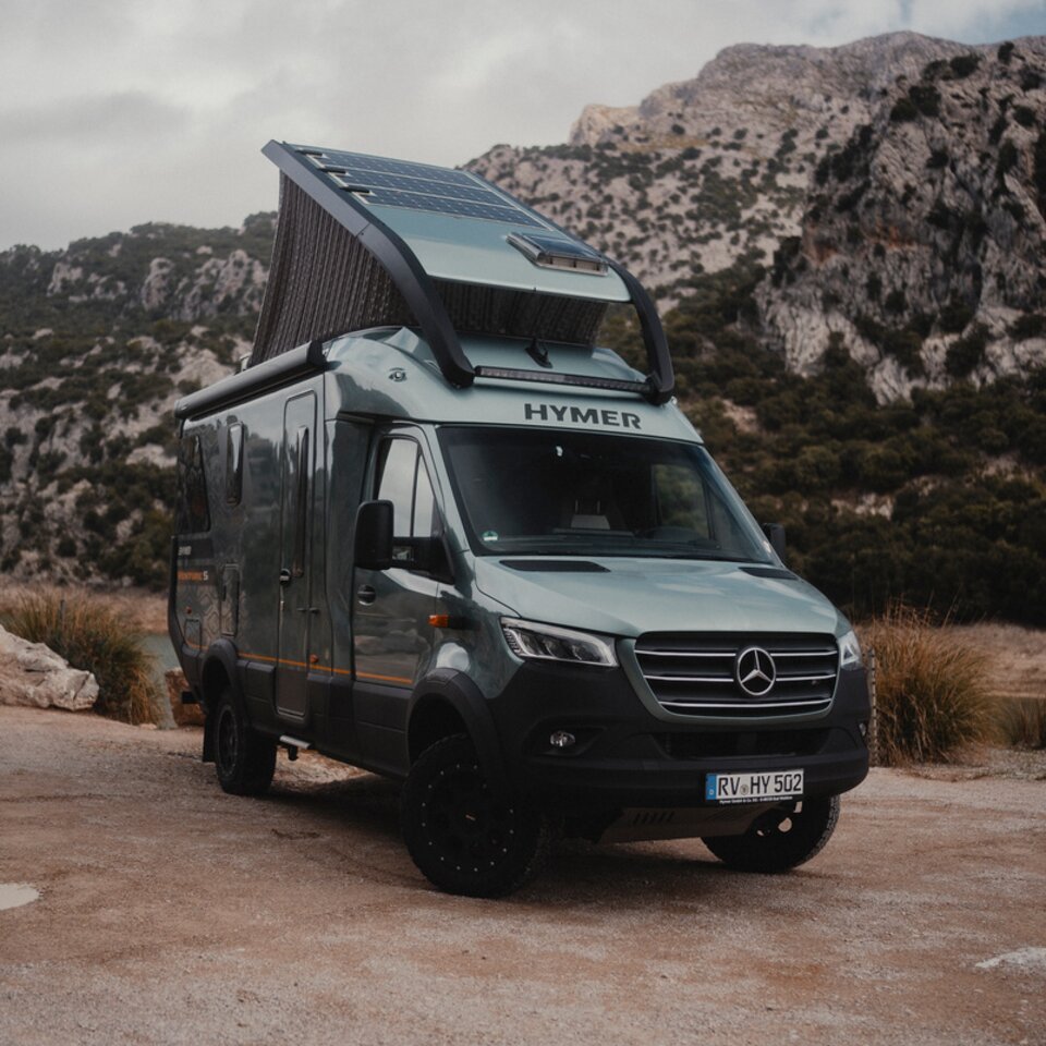 View from the front side of the Venture S, with the pop-top extended, mountains in the background.
