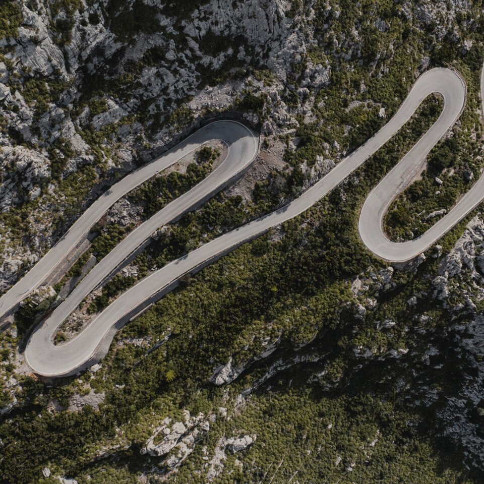 Aerial view of winding roads, surrounded by rocks and trees.