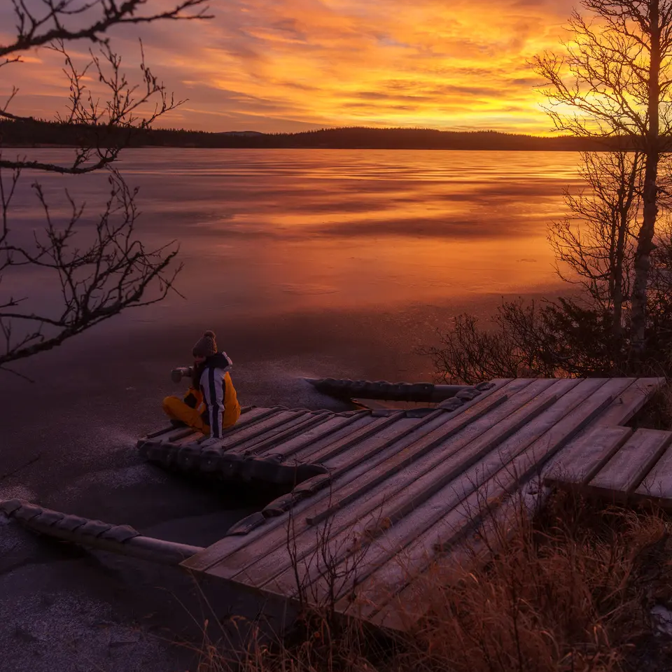 Udsigt over en kaj ved søen, smuk solnedgang i baggrunden