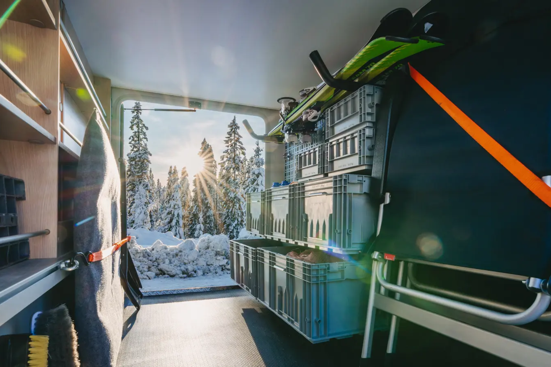 Udsigt gennem bagagerummet på HYMER B-MC T BlackLine, forskellige ting opbevaret i bagagerummet, en snedækket skov i baggrunden