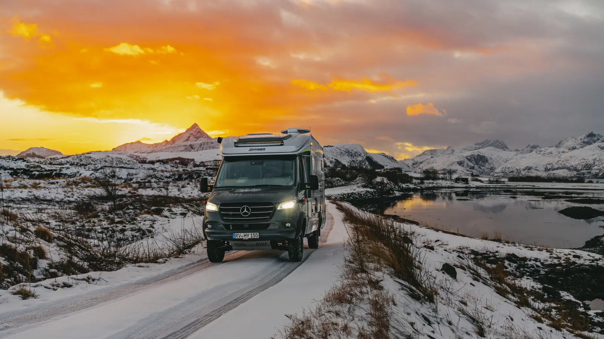 HYMER ML-T 570 kører på vejen, sneklædte bjerge og en smuk solnedgang i baggrunden