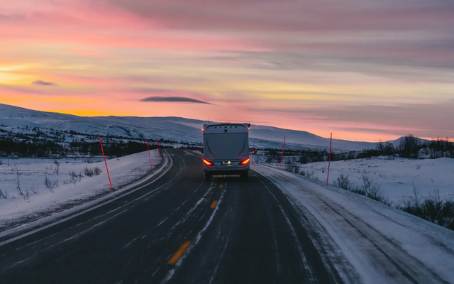 HYMER B-MC T BlackLine kører på en vej, bagudsigt, smuk solnedgang i baggrunden