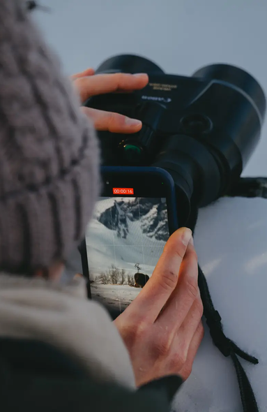 Kvinde filmer med sin telefon gennem en kikkert
