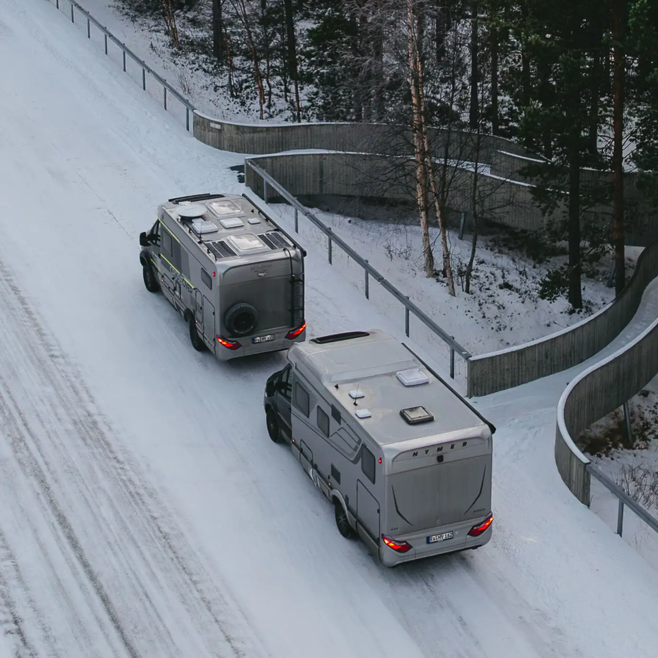 Vue aérienne du HYMER B-MC T BlackLine et du HYMER ML-T 570 CrossOver, garés sur une route enneigée