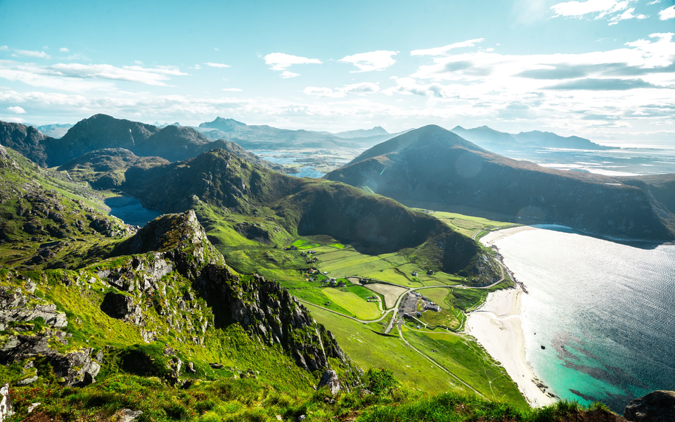 Vue des montagnes en Norvège, avec la mer à droite, sous un ciel bleu ensoleillé